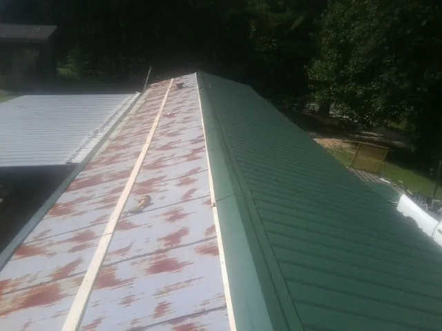 Old rusted panels beside newly installed green metal roofing — Wind Damage Roof Repair by Roofing Brothers in Harwood