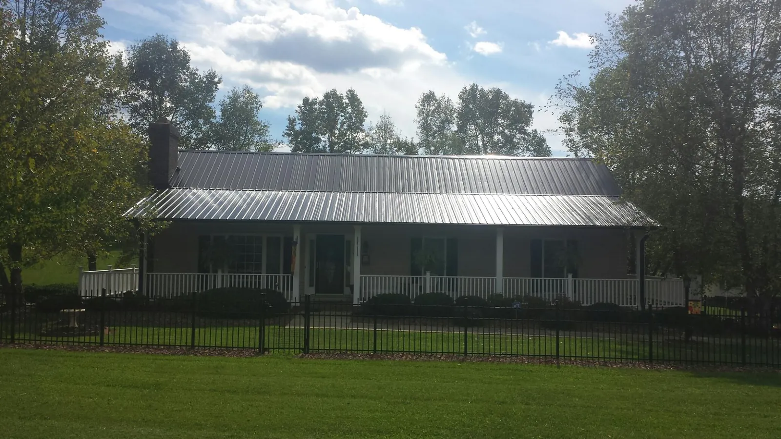 Gray metal roof on a brick ranch with a full width front porch — Gutter Guard Installation work by our crew in Harwood